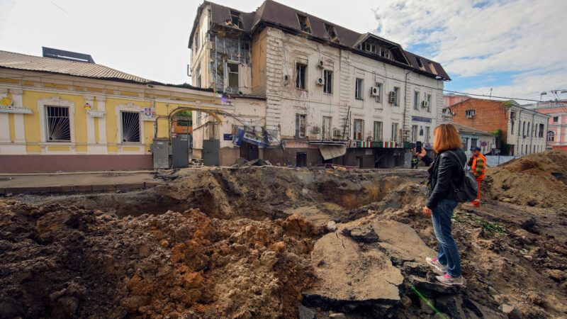 A woman in Kharkiv, Ukraine, stands in the crater left by a Russian shell and takes pictures of the rubble on her cell phone. | V Madiyevskyy/Ukrinform/SIPA/Newscom