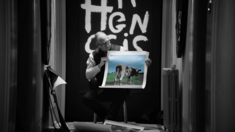 A man is shown holding a picture of a cow | Courtesy of Anton Corbijn