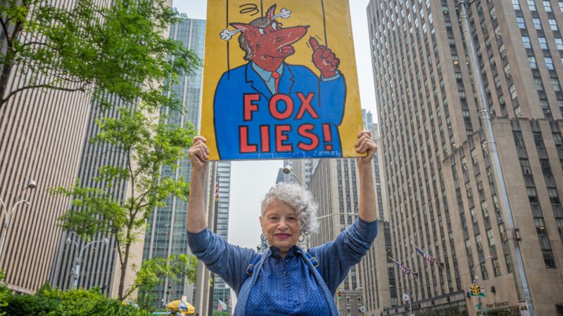 Protester wields sign outside of Fox News headquarters | Erik McGregor/Sipa USA/Newscom