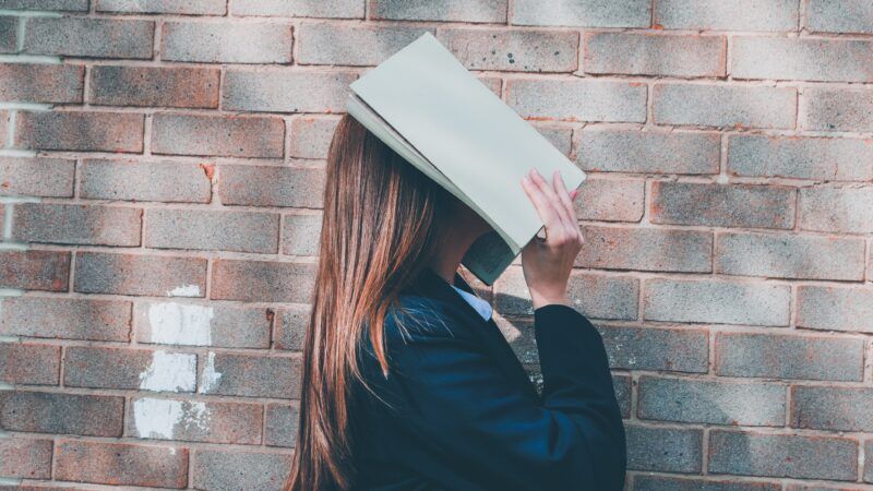 high school girl with book over her face | Photo by <a href="https://unsplash.com/@siora18?utm_source=unsplash&utm_medium=referral&utm_content=creditCopyText">Siora Photography</a> on <a href="https://unsplash.com/photos/K-g-Kt1vAHs?utm_source=unsplash&utm_medium=referral&utm_content=creditCopyText">Unsplash</a>   