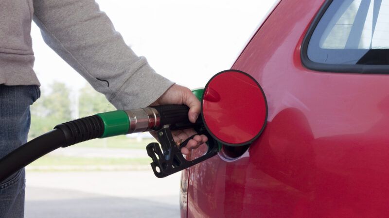 A motorist fuels up a red car. | Tatagatta | Dreamstime.com