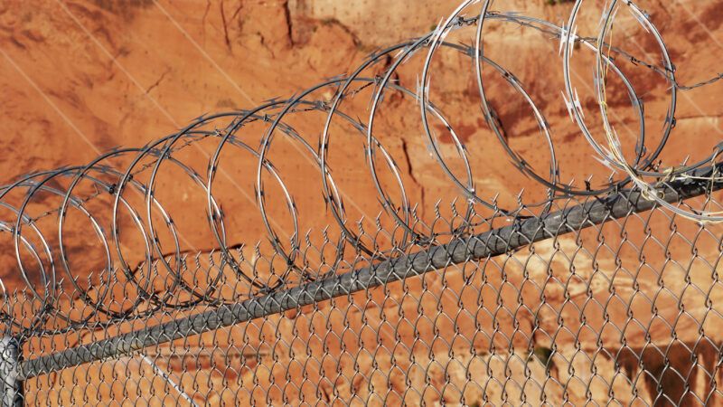 Chain-link fence topped with razor wire. | Jim Parkin | Dreamstime.com