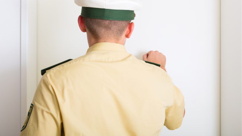 An officer, seen from behind, knocks on a door. | Arne9001 | Dreamstime.com