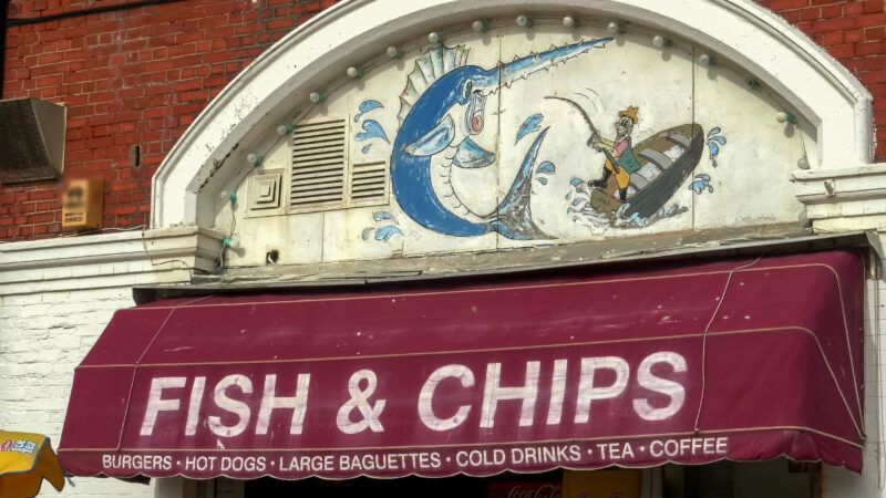 Awning that hangs over the entrance of an English restaurant, reading FISH & CHIPS | Christopher Bellette | Dreamstime.com