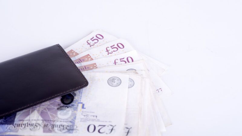 A black wallet with British pounds sticking out. | Piotr290 | Dreamstime.com