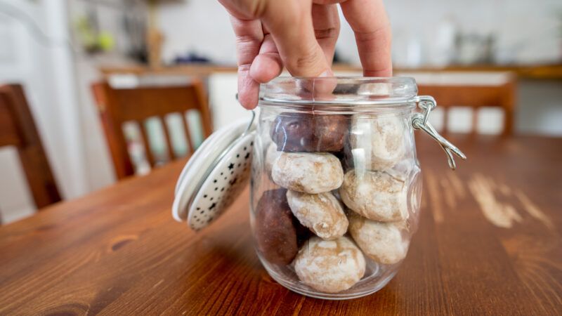 A hand reaches into a cookie jar to take a cookie. | Anderm | Dreamstime.com