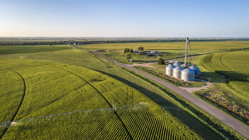 Aerial view of corn field with sprinkler, grain bins, and farm buildings. | Photo 122849023 © Marek Uliasz | Dreamstime.com