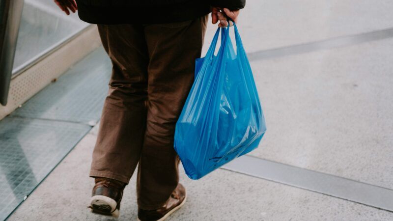 A person carries a blue plastic bag full of things | Photo by Mathias Reding on Unsplash