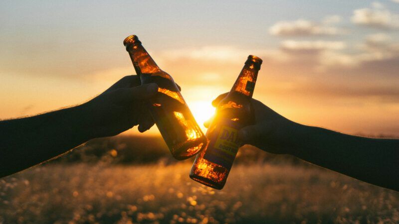 Two people clinking their beers at sunset | Photo by Wil Stewart on Unsplash