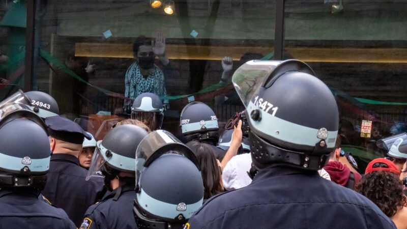 Students inside the Columbia University encampment look out the window over a sea of NYPD in riot gear. | Photo: Syndi Pilar/ZUMAPRESS/Newscom