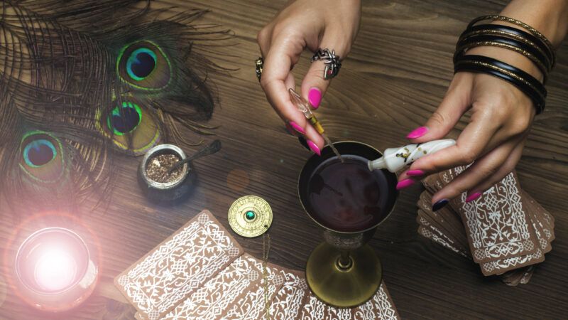 A witch's hands stir a magic potion on a table near tarot cards | Filindmitriy86 | Dreamstime.com