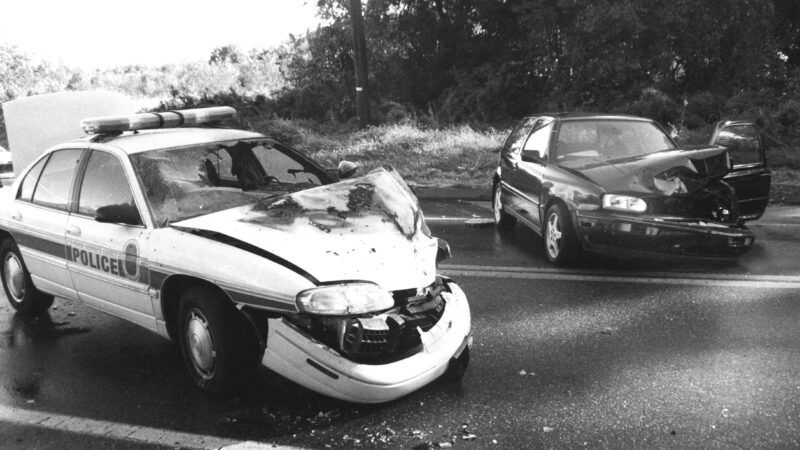 Black-and-white image of a car accident involving a dark sedan and a police car, each with extensive front-end damage. | Thomas Carter | Dreamstime.com