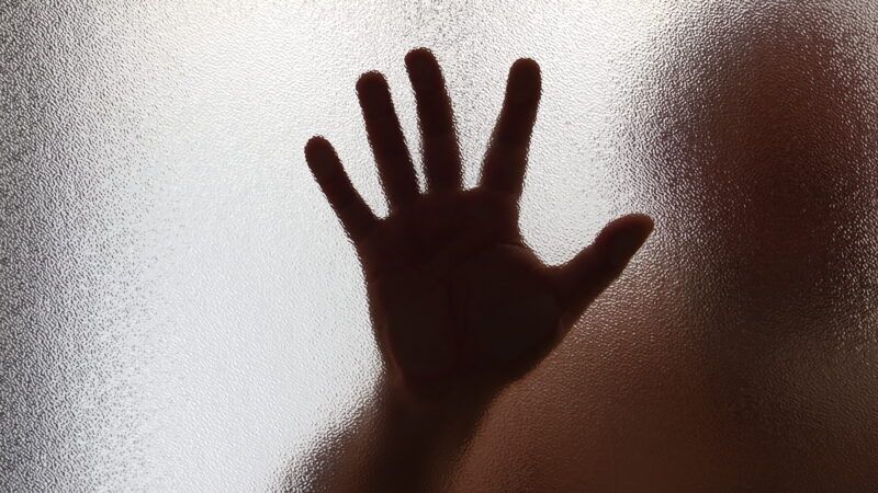 Human hand up against a window | NayalyH/Newscom