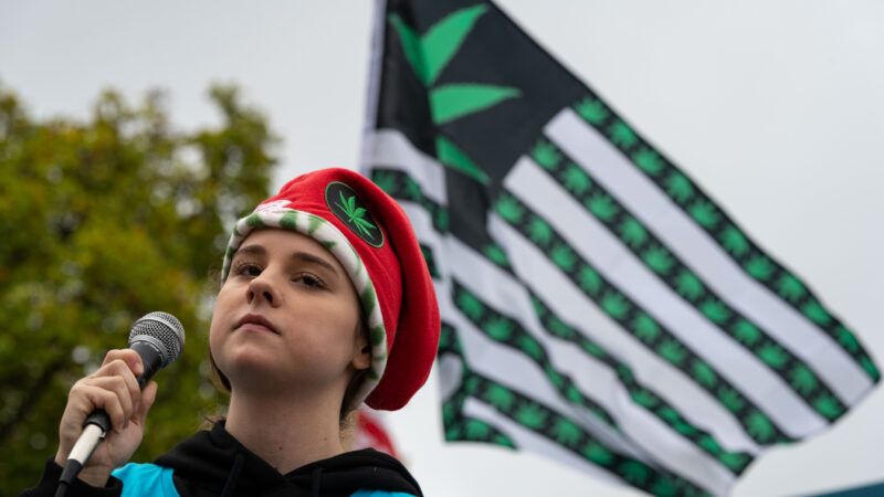 An activist wearing a hat with a marijuana leaf on it holds a microphone, in front of an American flag covered with marijuana leaves. | 	Alejandro Alvarez/Sipa USA/Newscom