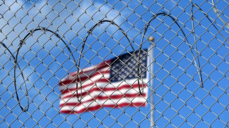 A U.S. flag flies behind barbed wire at the Guantánamo Bay naval base in Cuba. | Magdalena Miriam Tröndle/dpa/picture-alliance/Newscom