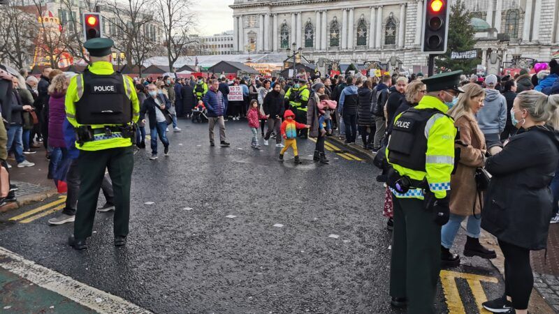 Crowd of protesters in Belfast, Northern Ireland, with police standing nearby. | Wirestock | Dreamstime.com 