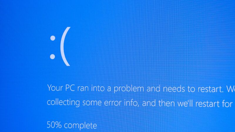 An emoticon frowny face against a blue computer background, with white text saying "Your PC ran into a problem and needs to restart"—the dreaded "Blue Screen of Death" for Microsoft users | Wutianzeri | Dreamstime.com