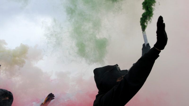 Protesters in silhouette amid red and green smoke | Fedecandoniphoto | Dreamstime.com