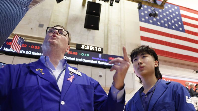 Two traders in blue jackets on the floor of the New York Stock Exchange. | John Angelillo/UPI/Newscom