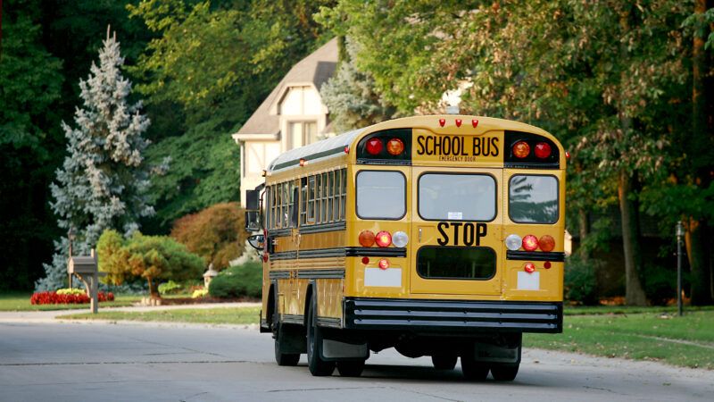 A yellow school bus drives through a residential neighborhood | Sonya Etchison | Dreamstime.com