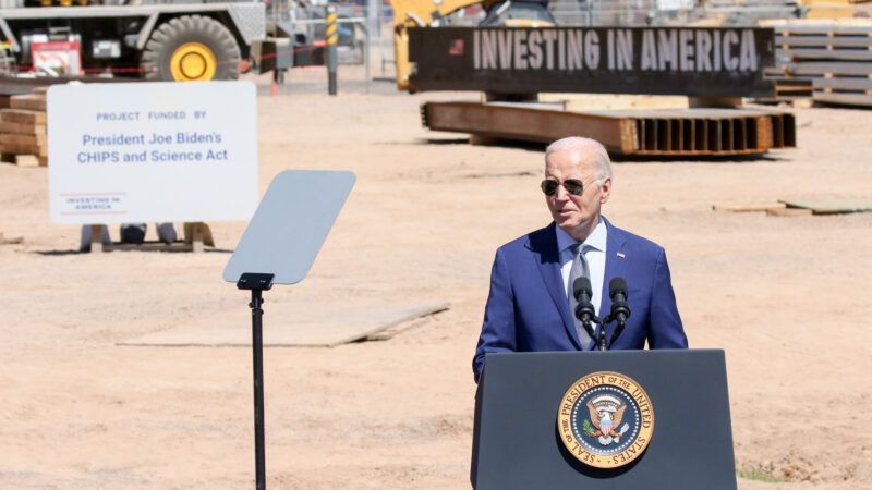 President Joe Biden speaks at a construction site at Intel's campus in Chandler, Arizona. There is a piece of equipment in the background with "INVESTING IN AMERICA" printed on the side and a sign that says "Project Funded by President Joe Biden's CHIPS and Science Act" | Alexandra Buxbaum/Sipa USA/Newscom