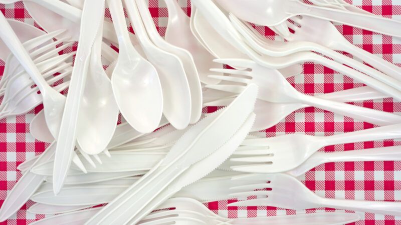 A pile of white plastic cutlery—forks, knives, spoons—on a red and white picnic table. | Bert Folsom | Dreamstime.com