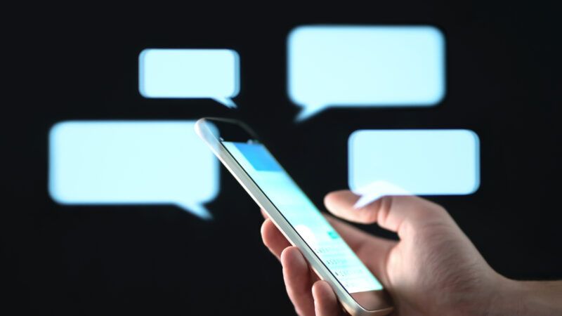 A hand holds a smartphone, while blank text bubbles float around in the background. | Tero Vesalainen | Dreamstime.com