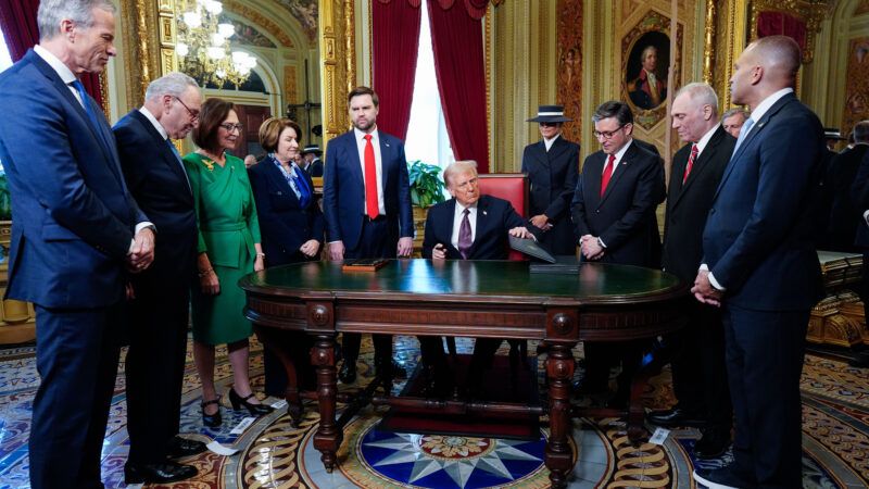 Trump signs documents at a desk surrounded by people | Melina Mara/UPI/Newscom