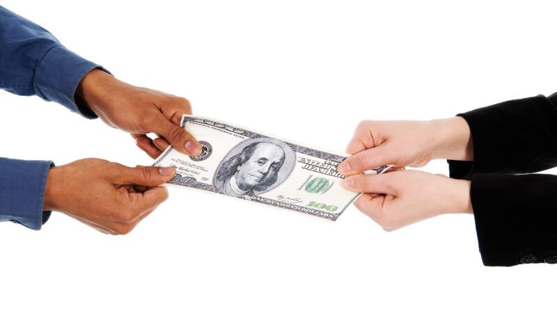 Two sets of hands, against a white background, pull on opposite ends of a U.S. $100 bill, as if in a tug of war. | Yanik Chauvin | Dreamstime.com