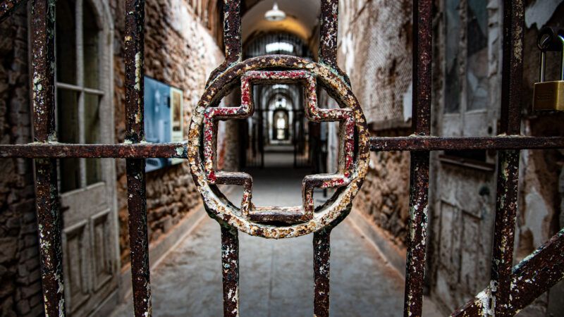 An old rusty gate in a prison. In the center of the gate, the bars form into a cross, suggesting an infirmary. | Ruben Martinez Barricarte | Dreamstime.com