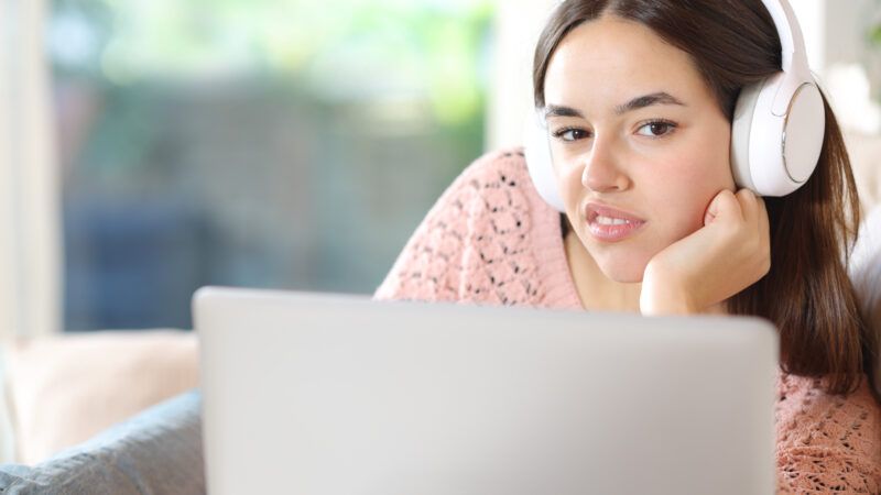 Woman on laptop with earphones on | 	AntonioGuillem/Newscom