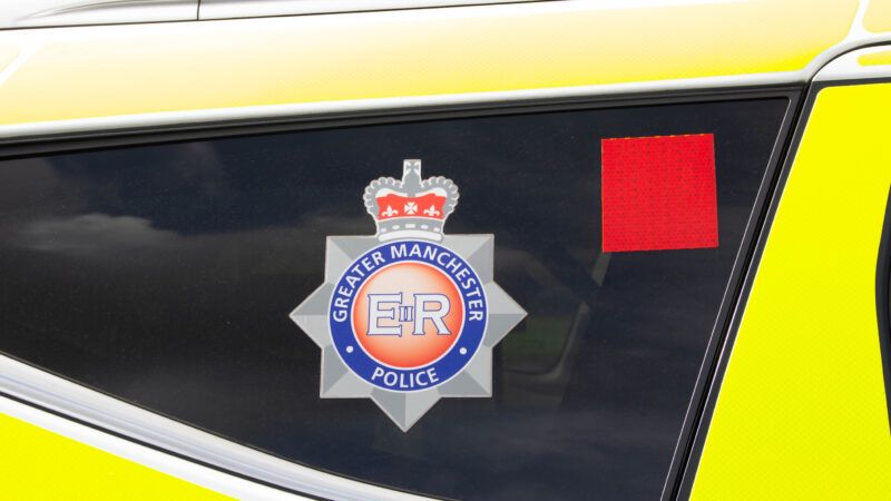 A Greater Manchester Police badge decal in the window of a police vehicle. | Garyjayuk8 | Dreamstime.com