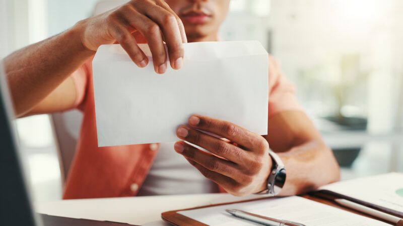 A man opens a small white envelope. | Yuri Arcurs | Dreamstime.com