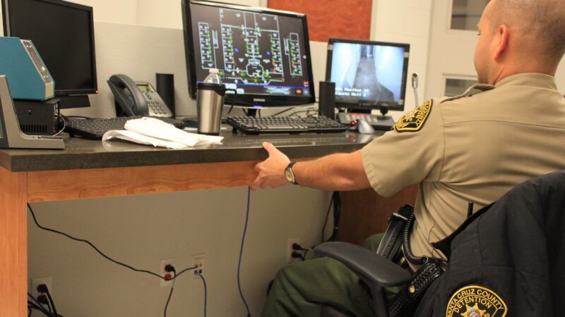 A prison guard sits at a desk in a guard station, surveying camera feeds. | Rebekah Zemansky | Dreamstime.com