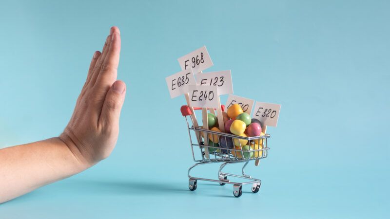 Mini shopping cart with food dye labels and a customer holding a hand out to keep it away | ID 369422970 @ Liudmila Lozovaia | Dreamstime.com