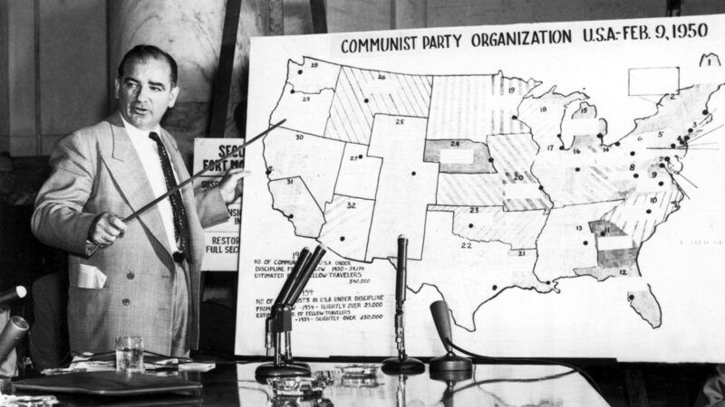 Joseph McCarthy standing in front of a map of Communist Party organizations across the United States in 1950 | Photo: Sen. Joseph McCarthy before Senate committee, 1950s; CSU Archives/Everett Collection/Alamy