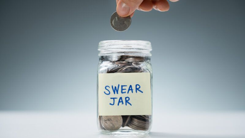 A hand lowers a quarter into a jar, labeled "SWEAR JAR," filled with coins. | Andrey Popov | Dreamstime.com