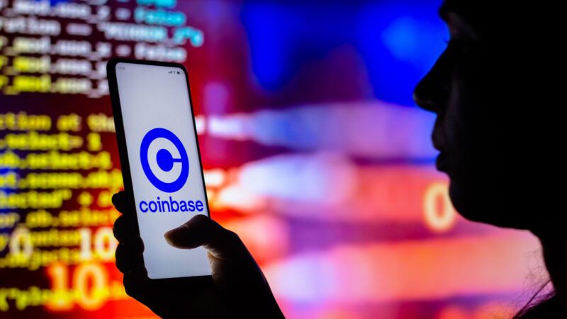 Person holding a phone with the Coinbase logo, in front of a wall of digital data. Person holding a phone with the Coinbase logo, in front of a wall of digital data. | https://x.com/Acyn/status/1918131457287176469