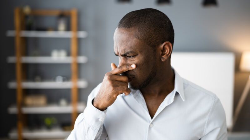 A man covers his nose, as if experiencing a terrible smell or something painful. | Andrey Popov | Dreamstime.com