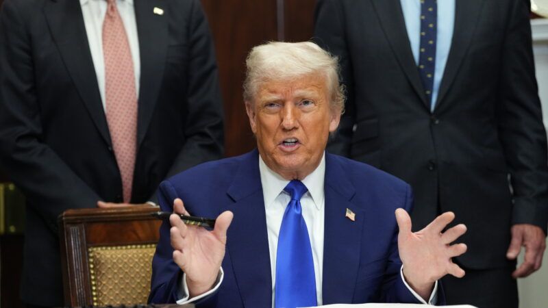 President Donald Trump addresses reporters while sitting at a desk to sign an executive order. | Chris Kleponis - via CNP/Polaris/Newscom