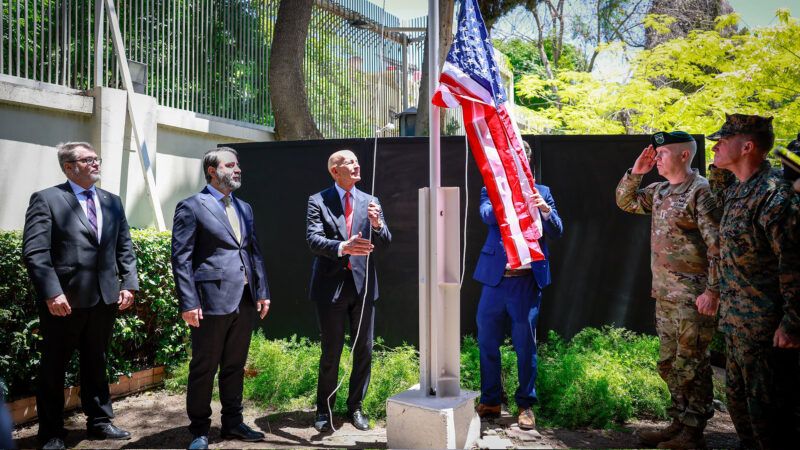 Syrian Foreign Minister Assaad al-Shibani looks on as U.S. Special Envoy Thomas Barrack raises the flag of the United States at the U.S. ambassador's residence in Damascus, Syria. May 29, 2025. | Syrian Arab News Agency (SANA)/UPI/Newscom
