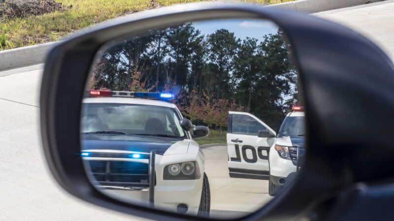 Police cars in a car side mirror reflection | ID 127985739 ©  Walter Arce | Dreamstime.com