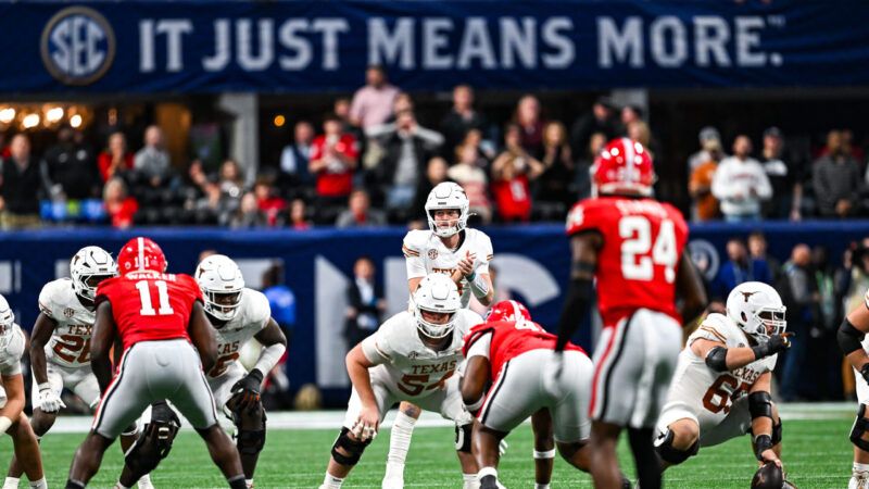 A presnap photo of a football game between Texas and Georgia, with Texas in their white jerseys and Georgia in their red ones. An SEC banner looms in the background with a slogan in all caps: "IT JUST MEANS MORE." | Rich von Biberstein/Icon Sportswire DKB/Rich von Biberstein/Icon Sportswire/Newscom