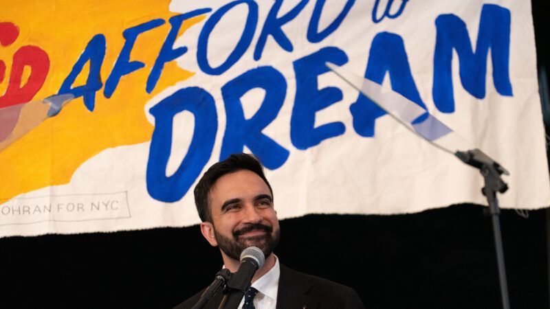 Zohran Mamdani stands in front of a campaign banner | Derek French/ZUMAPRESS/Newscom