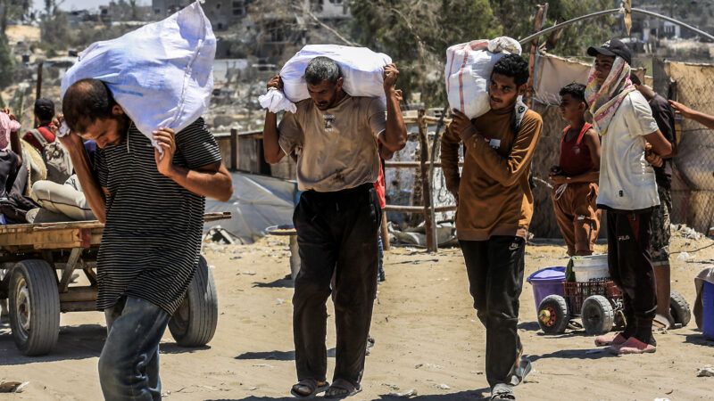 Palestinians carry sacks of flour after humanitarian aid supplies were airdropped by Qatari airplane over the Gaza Strip. 31 July 2025. | Abed Rahim Khatib/dpa/picture-alliance/Newscom