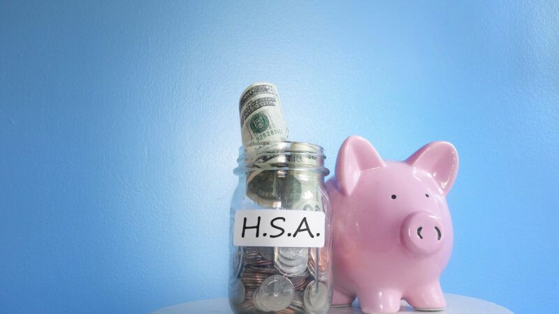 A piggy bank next to a jar of cash with a label that says "H.S.A." | Zimmytws | Dreamstime.com