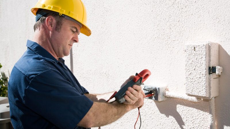An electrician checks the voltage on an outdoor receptacle near a junction box. | Brian T. Young | Dreamstime.com