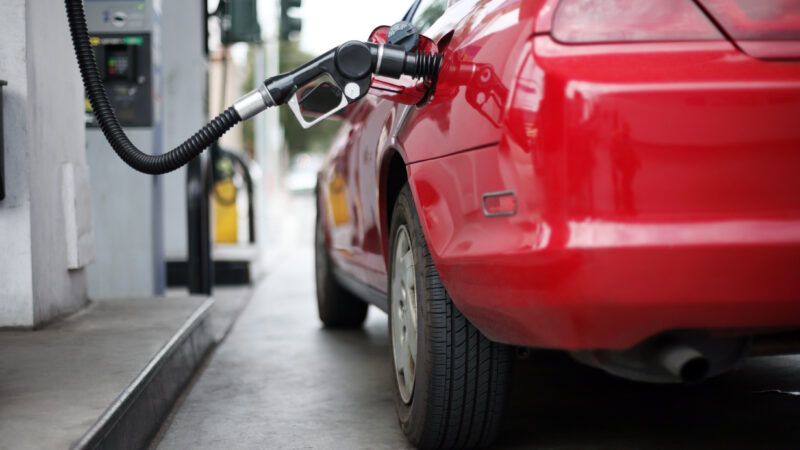 A red car sits at a gas station fuel pump with the nozzle inserted. | Konstantin Sutyagin | Dreamstime.com
