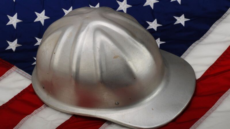 A silver hard hat for construction, sitting on an American flag. | W.scott Mcgill | Dreamstime.com