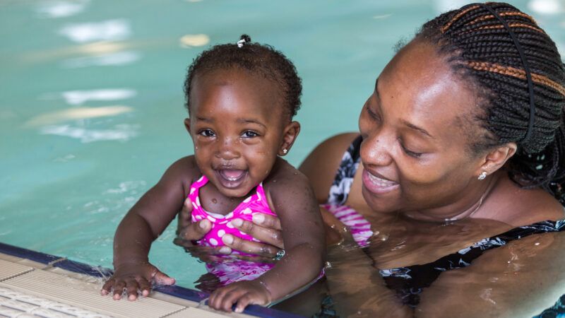 A smiling mother holds her happy daughter in a swimming pool. | Arinahabich08 | Dreamstime.com